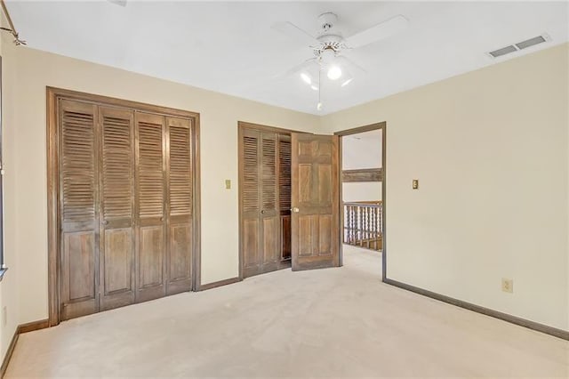 unfurnished bedroom with visible vents, two closets, light carpet, baseboards, and a ceiling fan