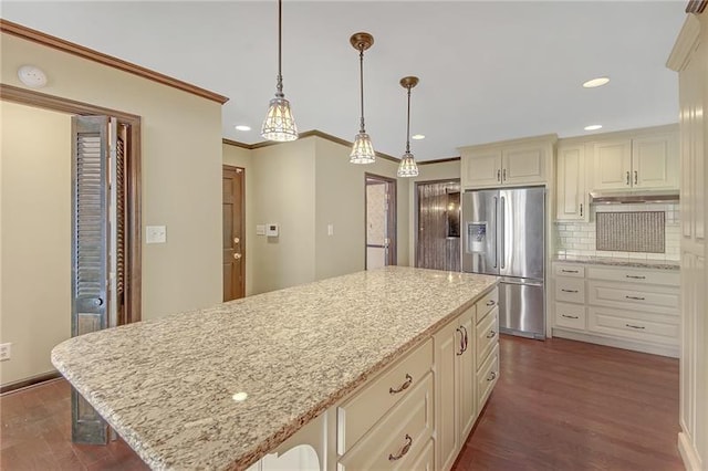 kitchen with tasteful backsplash, light stone countertops, dark wood finished floors, stainless steel fridge with ice dispenser, and cream cabinetry
