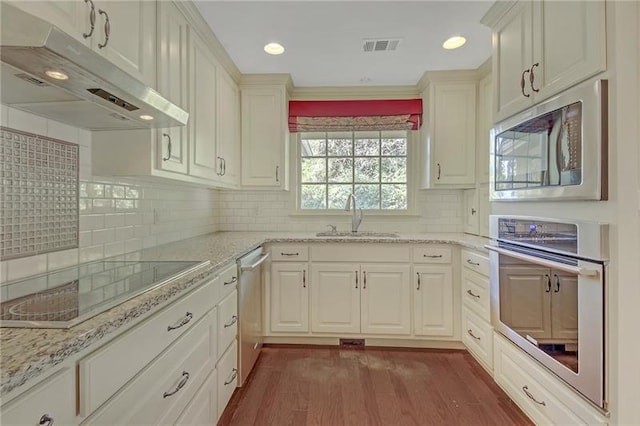 kitchen featuring dark wood-style flooring, visible vents, appliances with stainless steel finishes, a sink, and under cabinet range hood