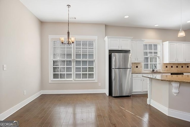 kitchen with decorative backsplash, white cabinets, and freestanding refrigerator