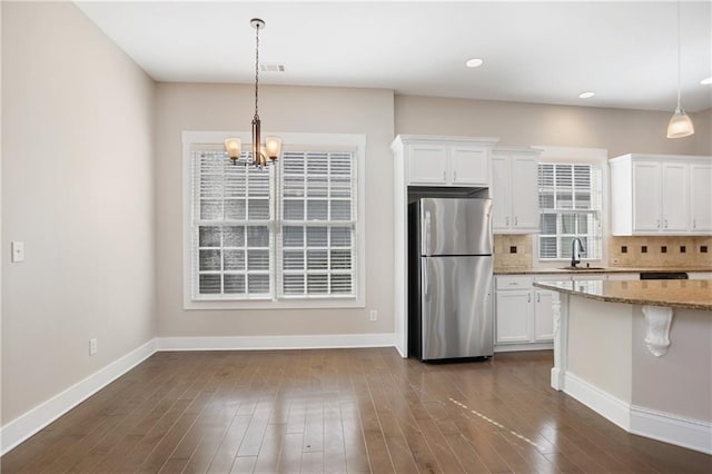 kitchen featuring visible vents, freestanding refrigerator, and white cabinetry