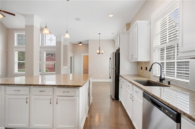 kitchen with stainless steel appliances, a sink, baseboards, white cabinetry, and hanging light fixtures