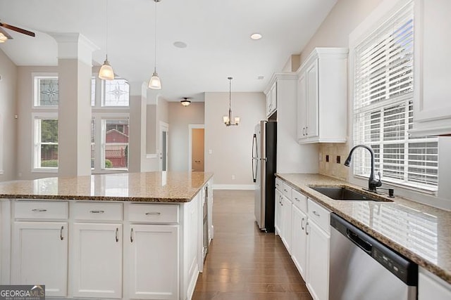 kitchen with a sink, tasteful backsplash, wood finished floors, white cabinetry, and stainless steel appliances