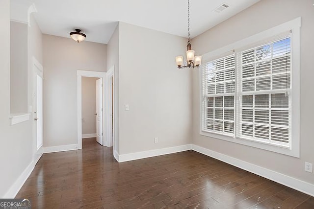 unfurnished dining area with dark wood finished floors, an inviting chandelier, baseboards, and visible vents