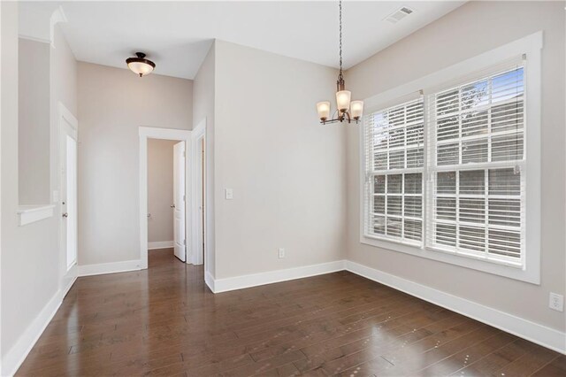 unfurnished dining area with baseboards, a notable chandelier, dark wood-type flooring, and visible vents