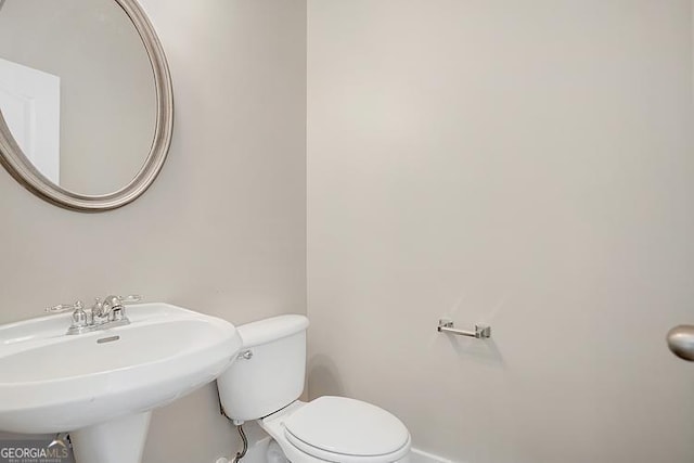 bathroom with a sink, baseboards, and toilet