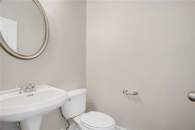 bathroom featuring baseboards, toilet, and a sink
