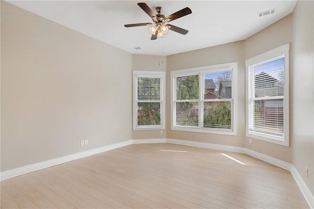 spare room with baseboards, a ceiling fan, visible vents, and light wood-type flooring