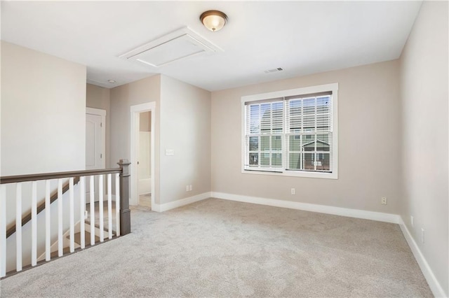 empty room with visible vents, attic access, baseboards, and carpet flooring