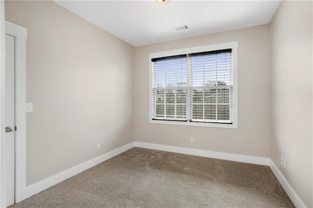 spare room featuring carpet floors, visible vents, and baseboards
