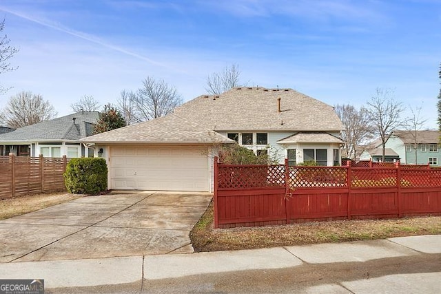 view of front of house with a garage, concrete driveway, and fence