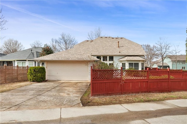ranch-style home with a garage, driveway, a fenced front yard, and roof with shingles