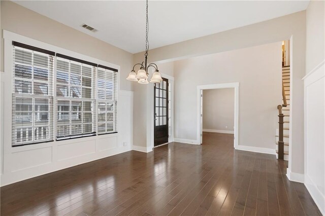unfurnished dining area featuring baseboards, visible vents, an inviting chandelier, and dark wood-style floors