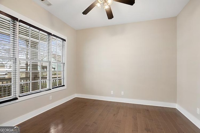 spare room with ceiling fan, visible vents, baseboards, and dark wood-style floors