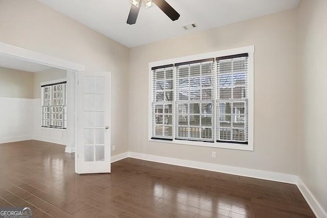 unfurnished room with visible vents, baseboards, dark wood-style floors, and a ceiling fan