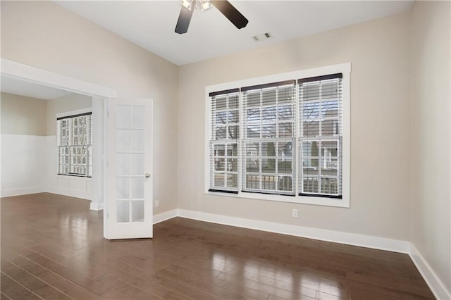 spare room with a ceiling fan, a healthy amount of sunlight, and dark wood-type flooring