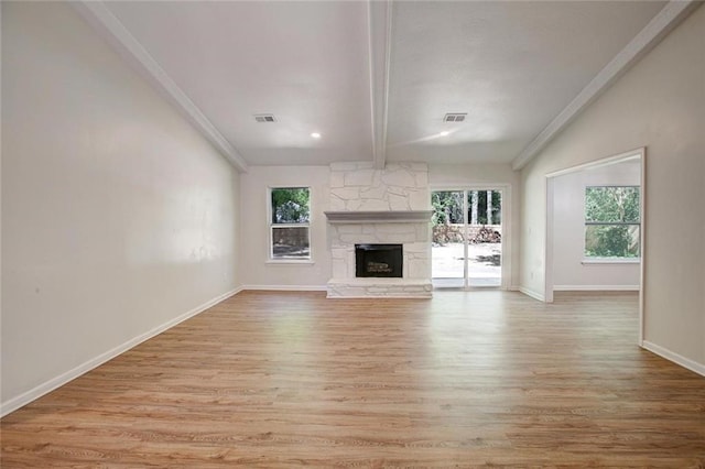 unfurnished living room featuring plenty of natural light, light wood-type flooring, vaulted ceiling with beams, and a fireplace