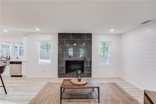 living area with light wood-style floors, recessed lighting, visible vents, and a high end fireplace