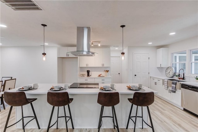 kitchen with island range hood, white cabinetry, visible vents, stainless steel dishwasher, and light wood-type flooring