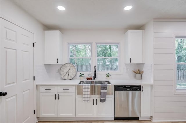 kitchen featuring decorative backsplash, dishwasher, light countertops, white cabinetry, and a sink