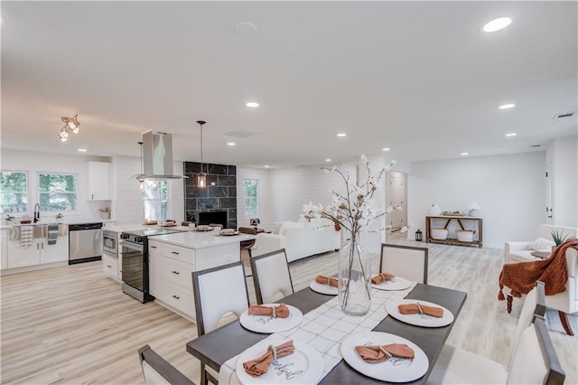 dining space with light wood-style floors, a high end fireplace, and recessed lighting