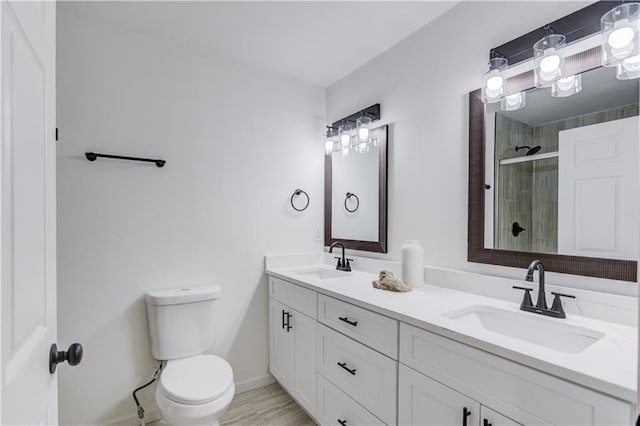 bathroom featuring a sink, a shower stall, toilet, and double vanity