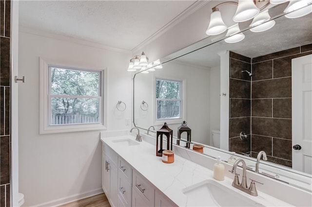 full bath featuring toilet, crown molding, a sink, and tiled shower