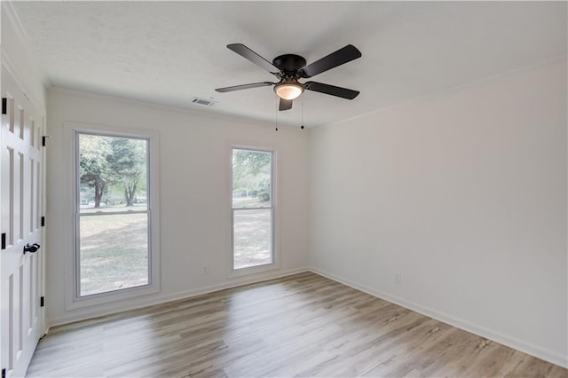 spare room featuring light wood finished floors, baseboards, visible vents, and ceiling fan