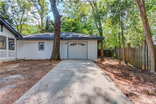 garage featuring driveway and fence