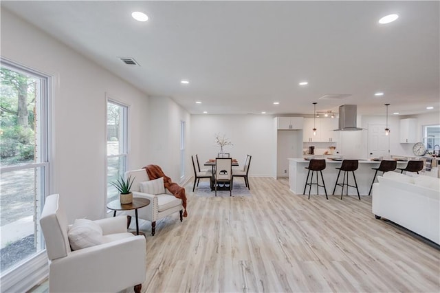 living room featuring light wood finished floors, baseboards, visible vents, and recessed lighting