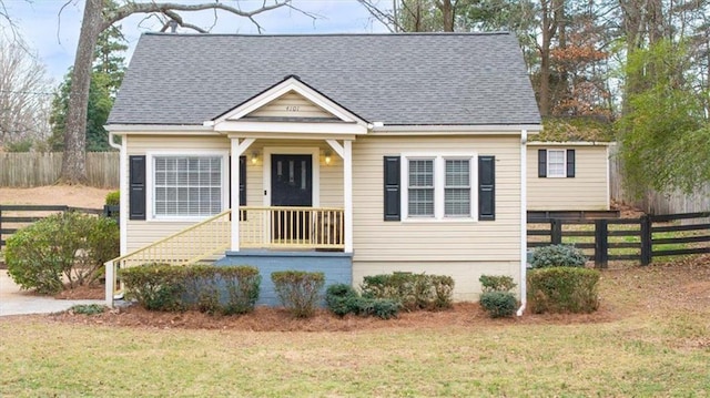 view of front of property with a shingled roof, a front yard, and fence