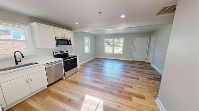 86 Martin Luther King Jr Dr, Jefferson, GA 30549 - kitchen featuring stainless steel appliances, a sink, light wood-type flooring, baseboards, and white cabinetry