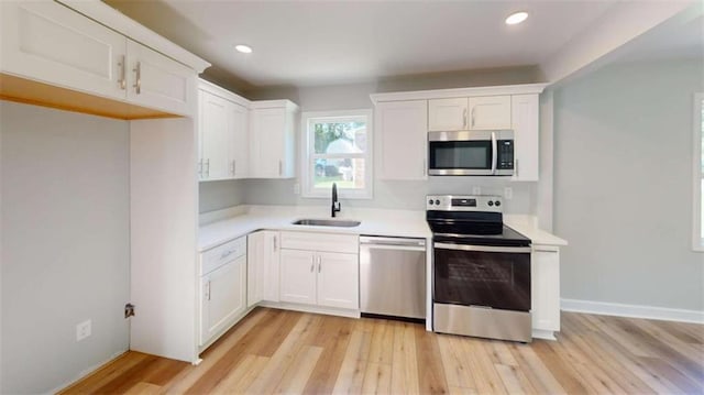 86 Martin Luther King Jr Dr, Jefferson, GA 30549 - kitchen with stainless steel appliances, a sink, light wood-style flooring, white cabinetry, and light countertops
