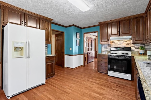 kitchen with white appliances, backsplash, crown molding, light hardwood / wood-style floors, and light stone counters