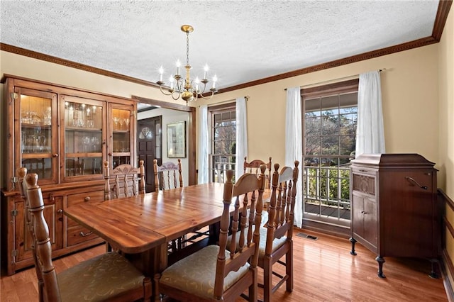 dining area featuring crown molding, light hardwood / wood-style flooring, a chandelier, and a textured ceiling