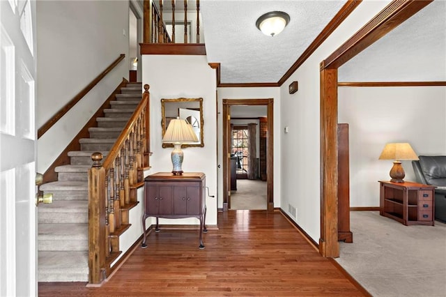 entrance foyer with crown molding, wood-type flooring, and a textured ceiling