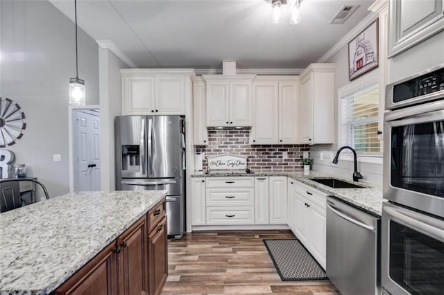 kitchen with stainless steel appliances, backsplash, a sink, and white cabinets