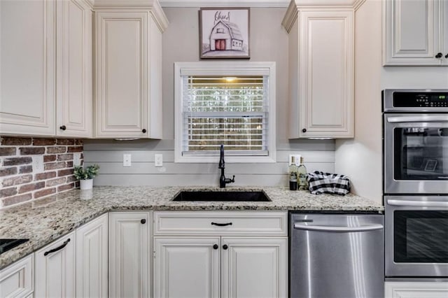 kitchen with stainless steel appliances, tasteful backsplash, a sink, and white cabinets