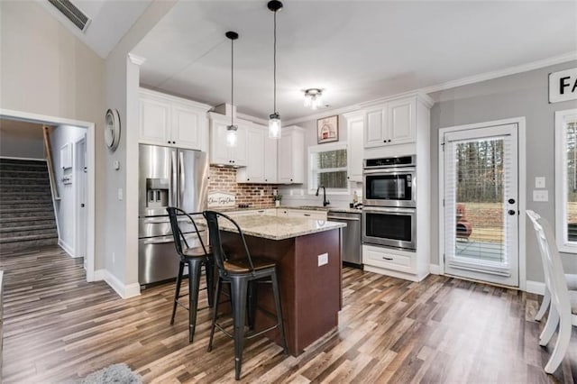 kitchen featuring a breakfast bar, appliances with stainless steel finishes, white cabinetry, a sink, and a kitchen island