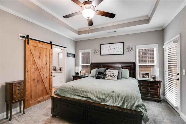 carpeted bedroom featuring baseboards, a barn door, a raised ceiling, and crown molding