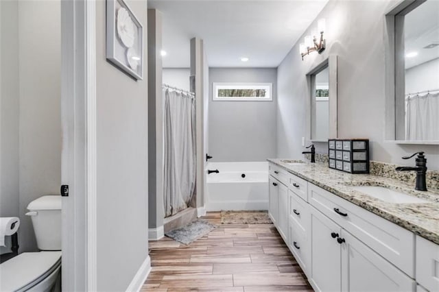 full bathroom with double vanity, a shower with shower curtain, toilet, a sink, and wood finished floors