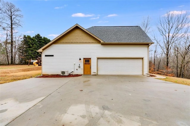 view of side of home featuring a shingled roof and concrete driveway