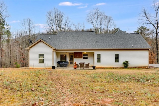 back of house featuring a yard, roof with shingles, and a patio