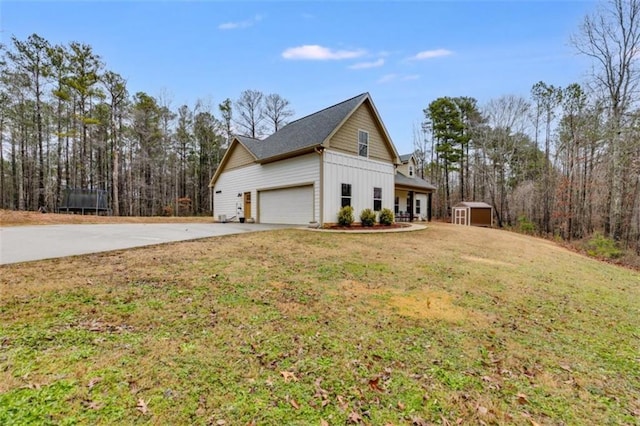 view of property exterior with a garage, driveway, a lawn, a shed, and board and batten siding