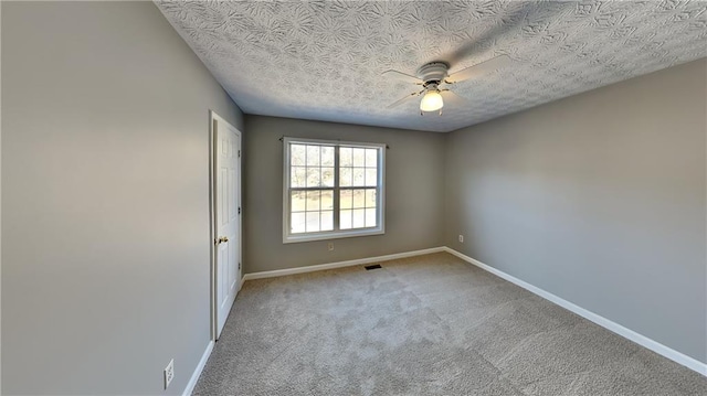 carpeted spare room featuring ceiling fan and a textured ceiling