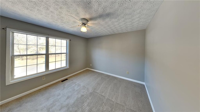 carpeted empty room featuring ceiling fan and a textured ceiling