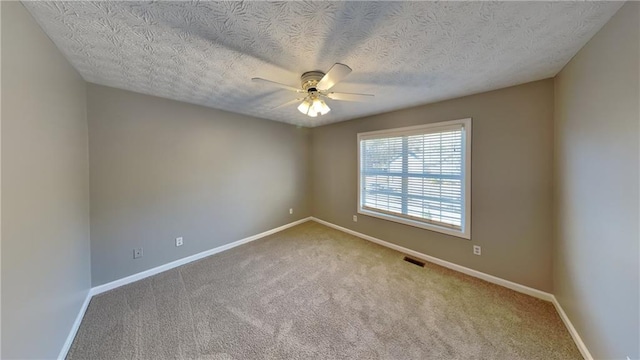 carpeted empty room with ceiling fan and a textured ceiling