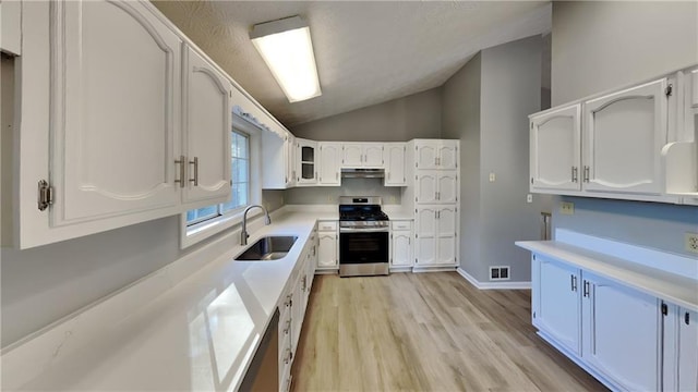 kitchen with vaulted ceiling, white cabinetry, sink, stainless steel range, and light hardwood / wood-style flooring