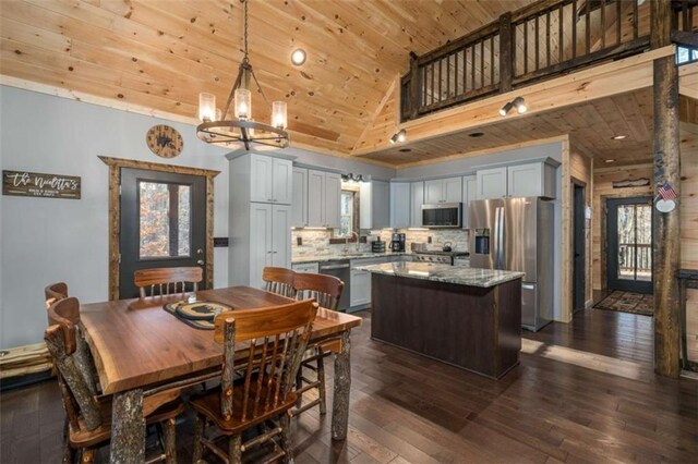 kitchen featuring decorative light fixtures, a center island, wood ceiling, light stone counters, and stainless steel appliances