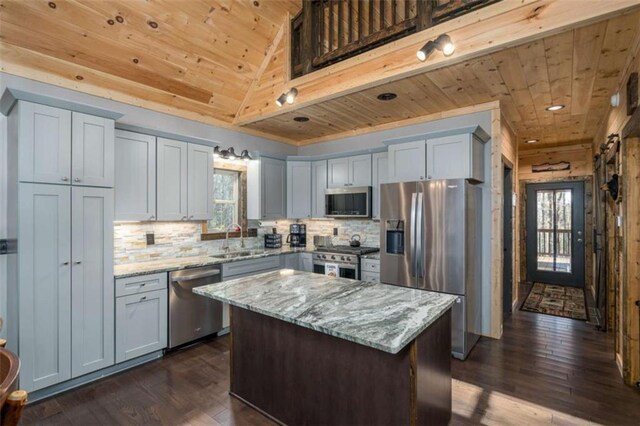 kitchen with sink, wood ceiling, appliances with stainless steel finishes, light stone counters, and a kitchen island